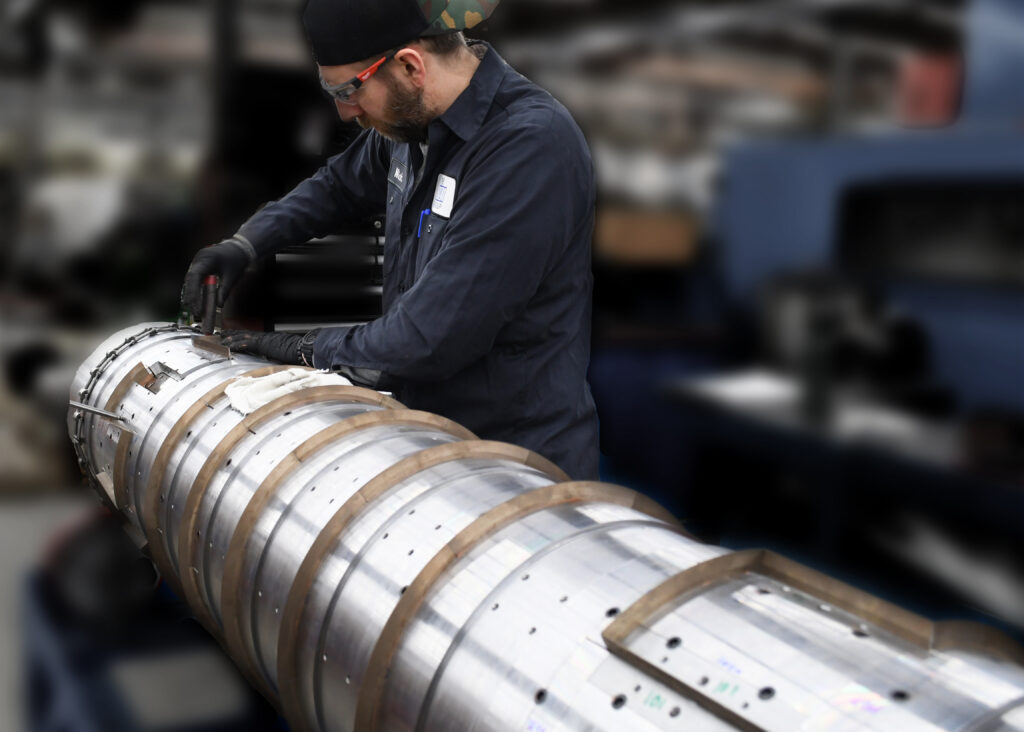 worker replacing shingle knives on a cutting cylinder as part of refurbishment